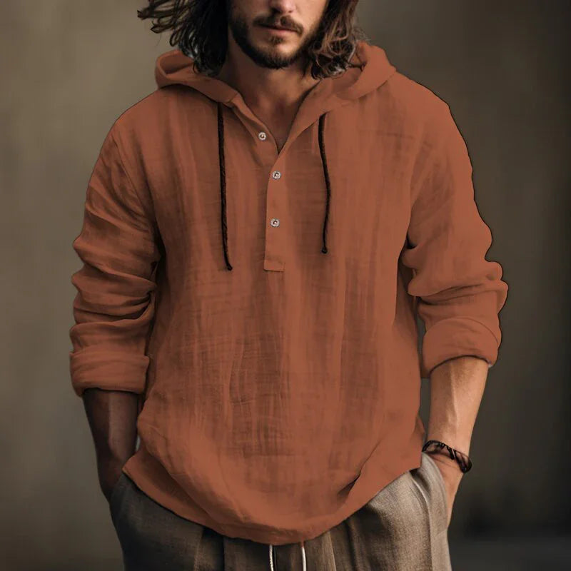 Man wearing a brown hooded shirt against a neutral background