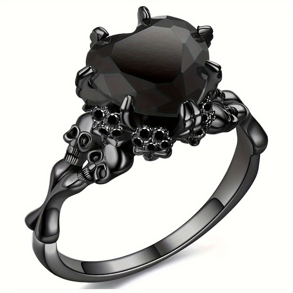 A gothic-style black ring featuring a large faceted black gemstone held by skull and crossbones motifs, set on a polished black band against a white background.