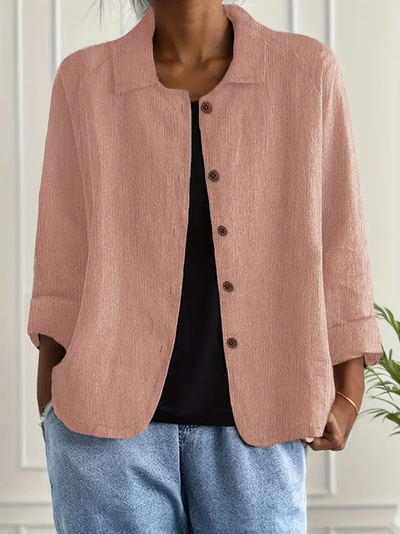 Person wearing a pink corduroy jacket over a black top and blue jeans, standing against a neutral background.