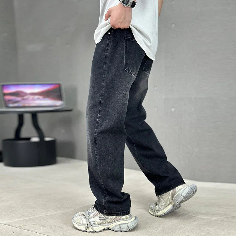 Person wearing black jeans and white sneakers in a room with a laptop on a desk.