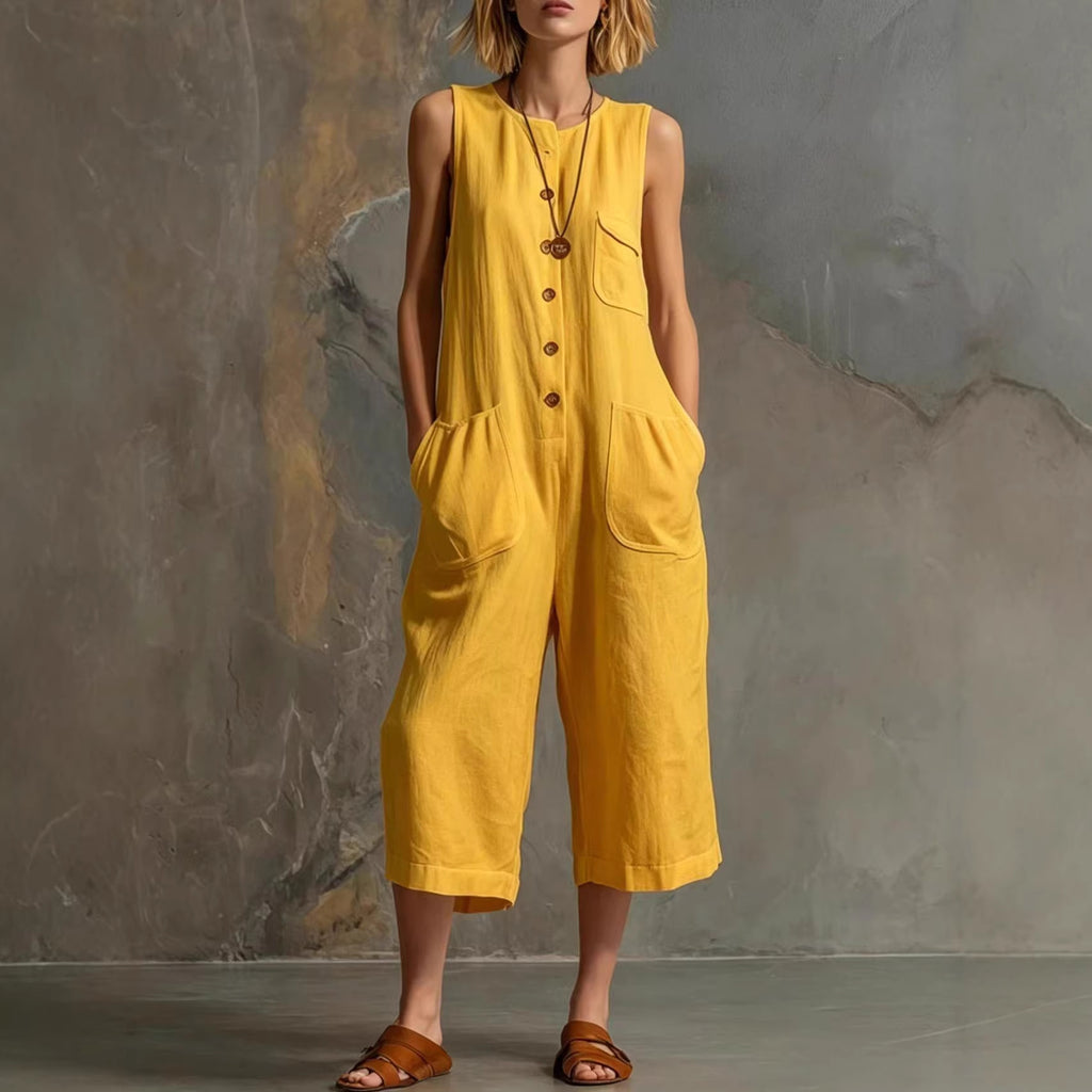Person wearing a yellow sleeveless jumpsuit against a textured wall.