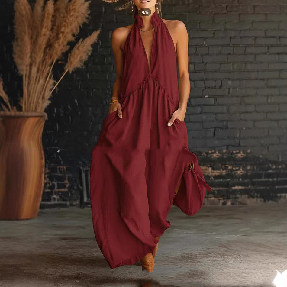 Woman wearing a burgundy halter neck dress against a brick wall.