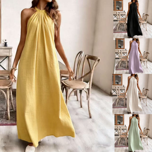 Woman wearing a yellow dress in a room with wooden chairs.