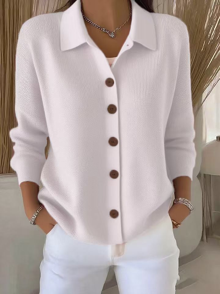 White button-up shirt with brown buttons worn by a person indoors.