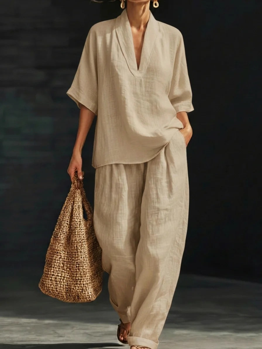 Person wearing a beige outfit holding a woven bag against a dark background
