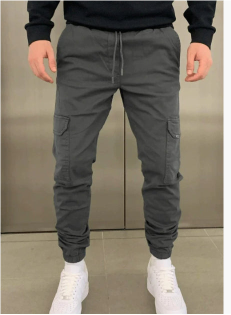 Person wearing gray cargo jogger pants with a neutral background