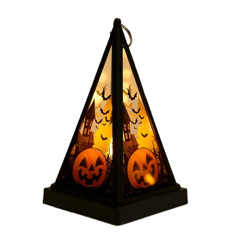 A black pyramid-shaped Halloween lantern with a glowing orange interior, featuring silhouettes of bats, a haunted house, and jack-o'-lanterns on a white background.