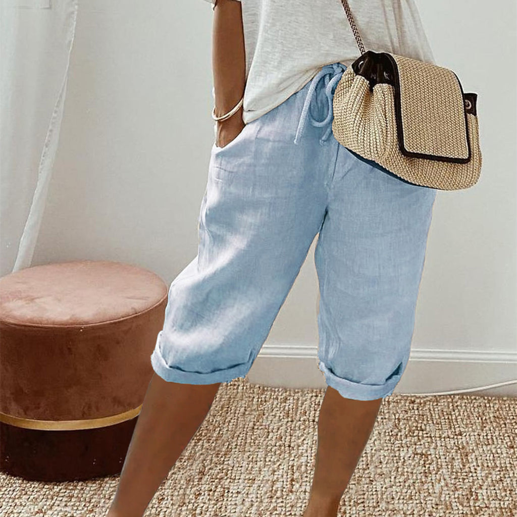 Person wearing light blue shorts and a straw bag, standing indoors.
