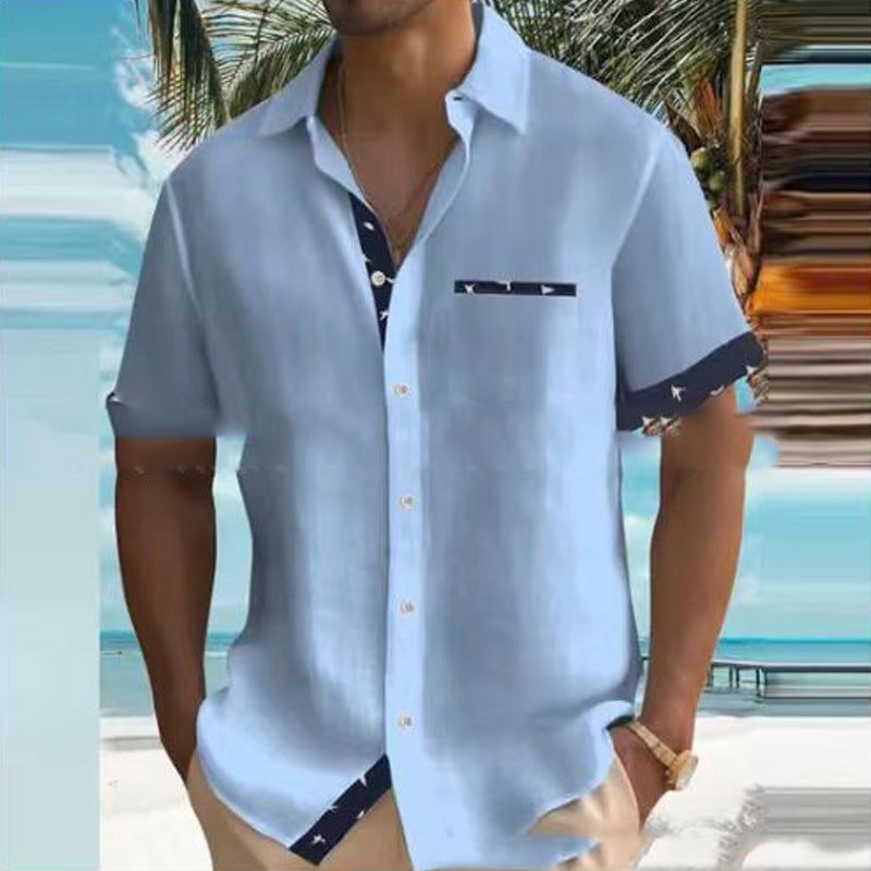 Light blue shirt with dark trim worn by a person on a beach.