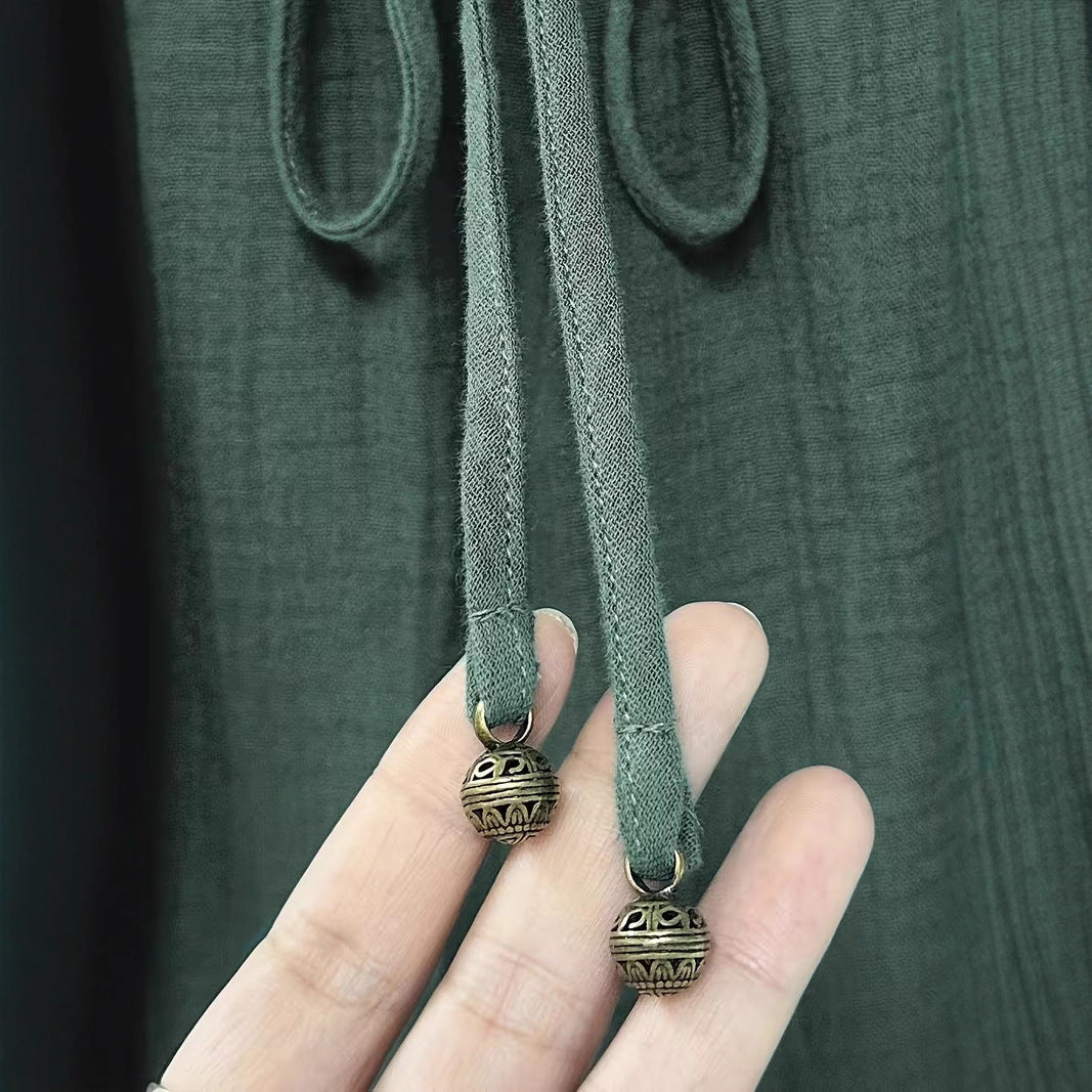 Hand holding a green fabric strap with decorative metal ends against a dark background