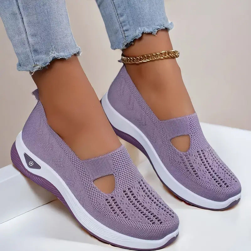Purple slip-on shoes with white soles worn with light blue jeans on a neutral background