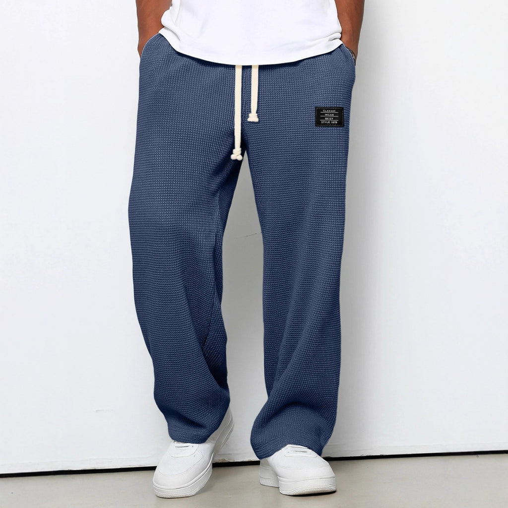 Person wearing blue textured sweatpants with a white label on a white background