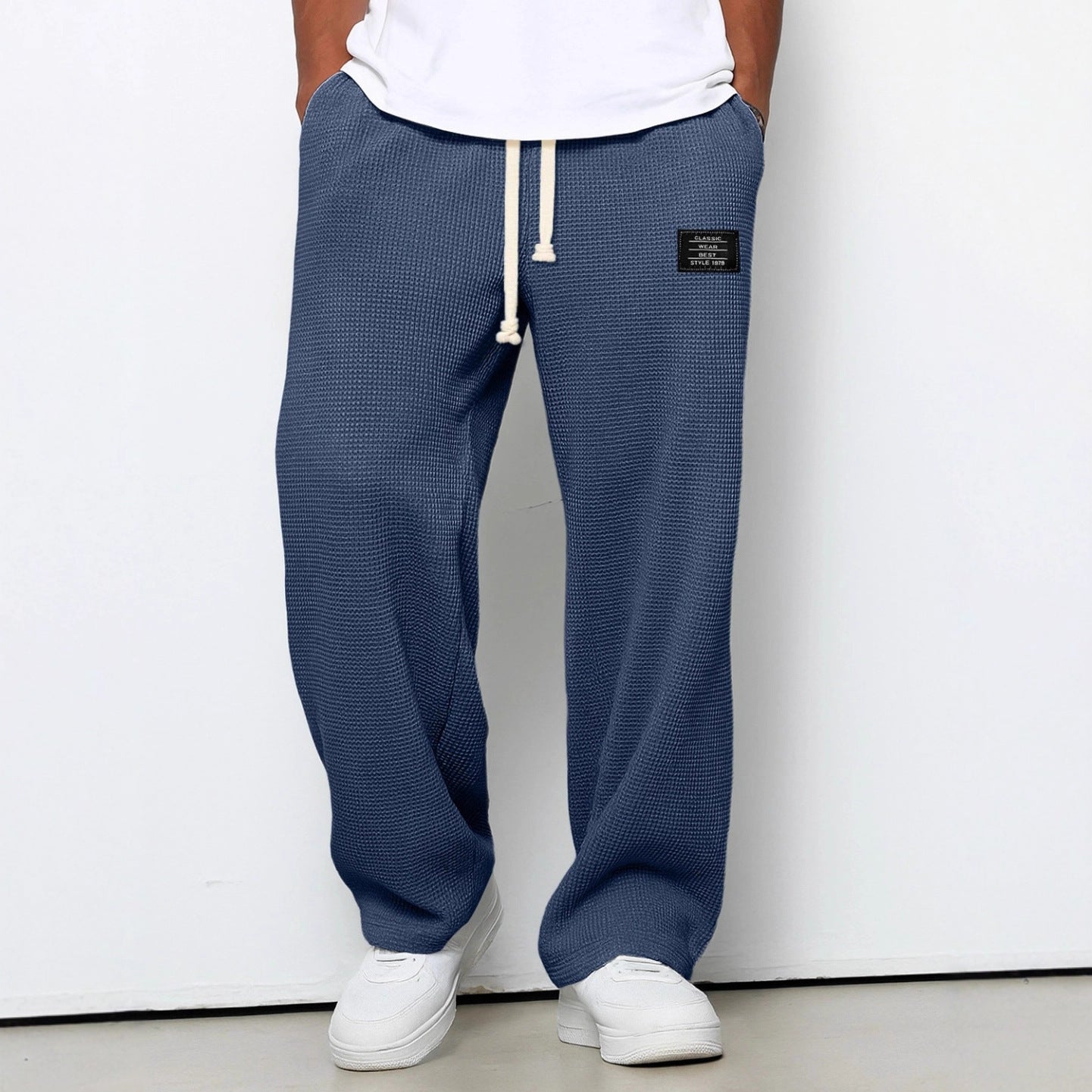 Person wearing blue textured sweatpants with a white label on a white background