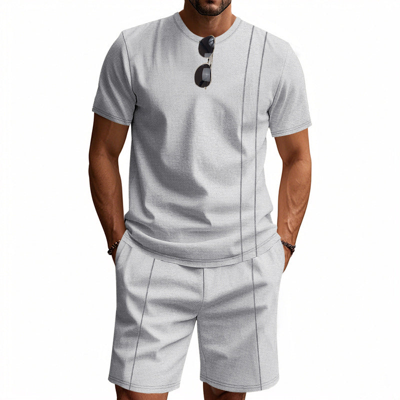 Man wearing a gray patterned shirt and shorts set with sunglasses on a white background