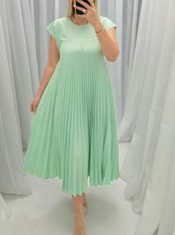 Person wearing a light green pleated dress against a white curtain background