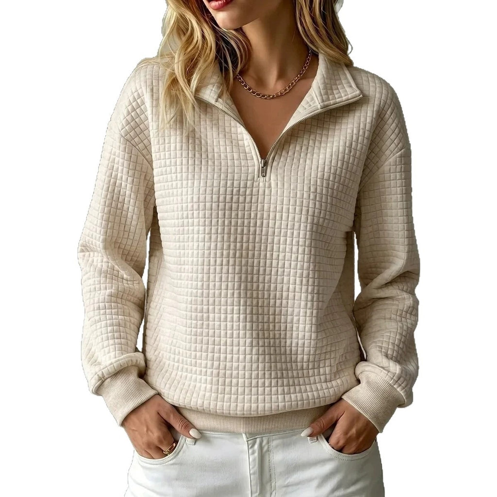 A woman wearing a cream-colored, textured quarter-zip pullover sweater with a stand collar, paired with white pants, shown against a plain white background.