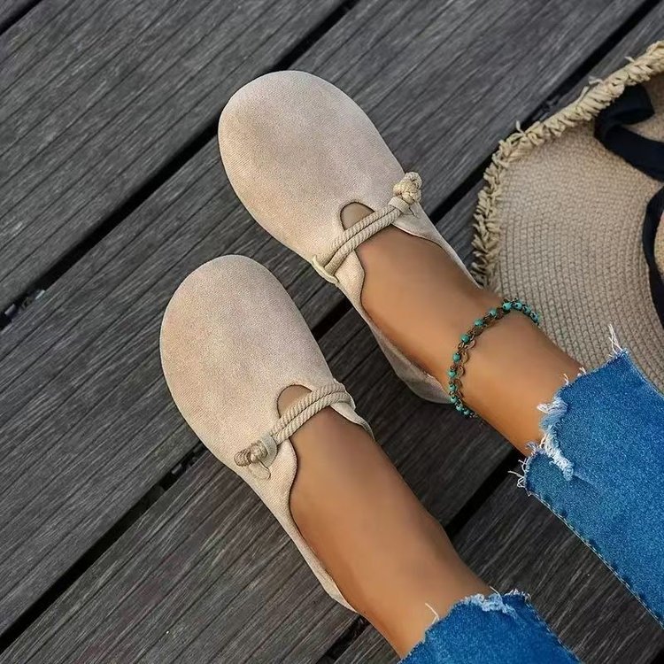 Beige loafers worn with blue jeans on a wooden floor