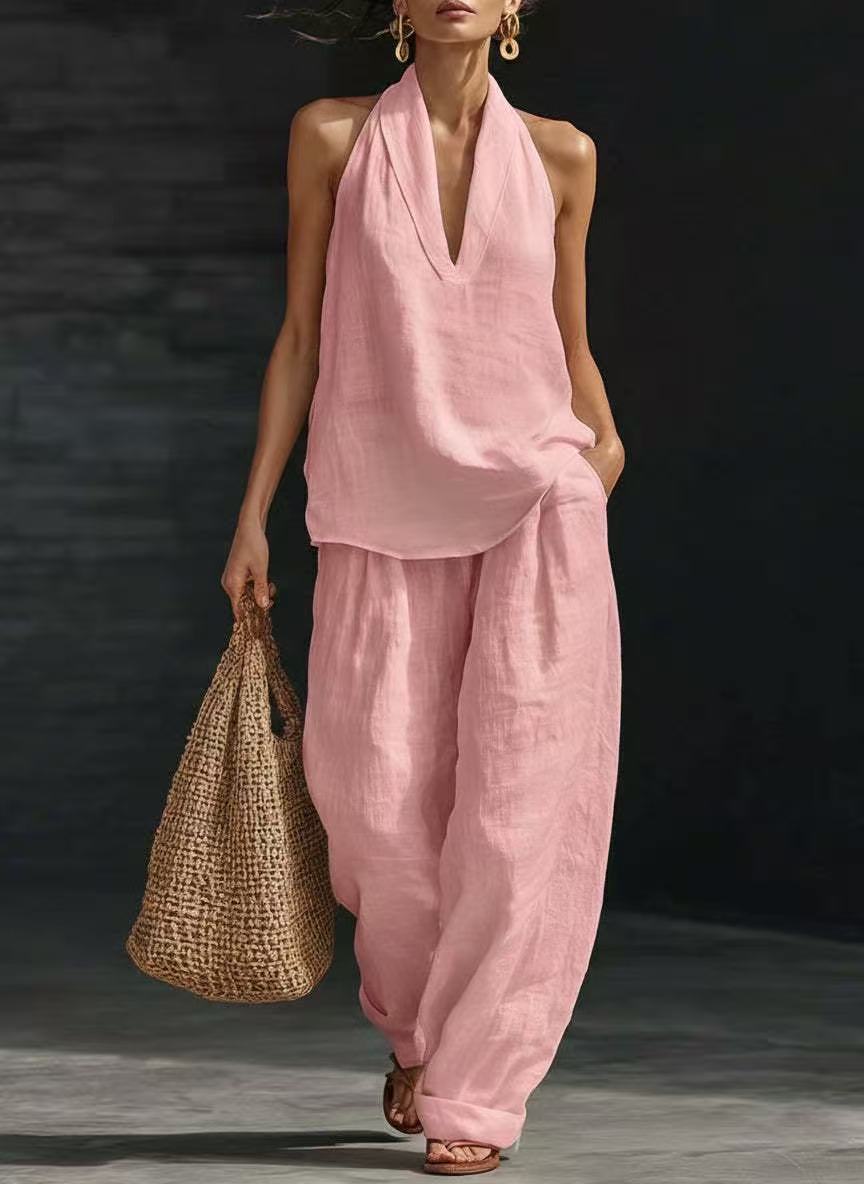Woman wearing a pink outfit holding a woven bag against a dark background