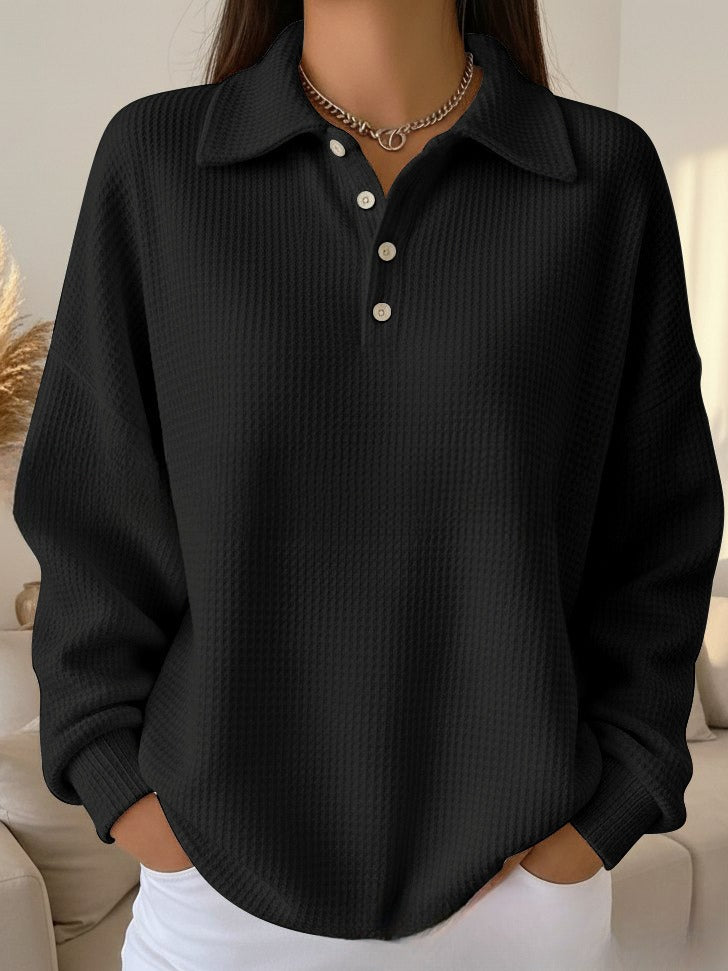 Black ribbed sweater with a collar worn by a person indoors.