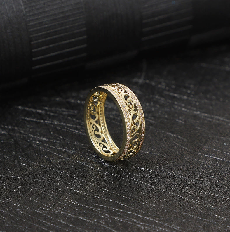Gold ring with intricate design on a black textured surface