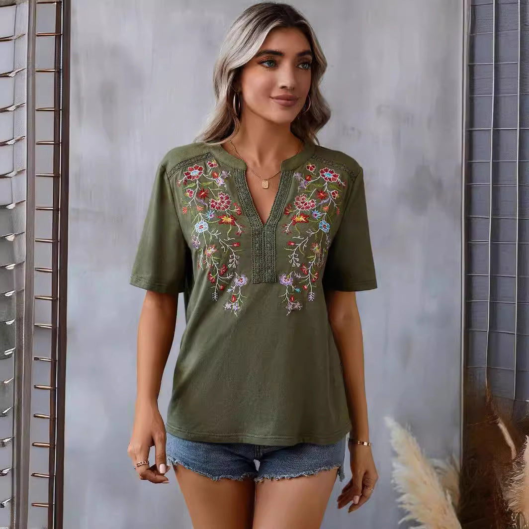 Woman wearing an olive green embroidered top with a neutral background