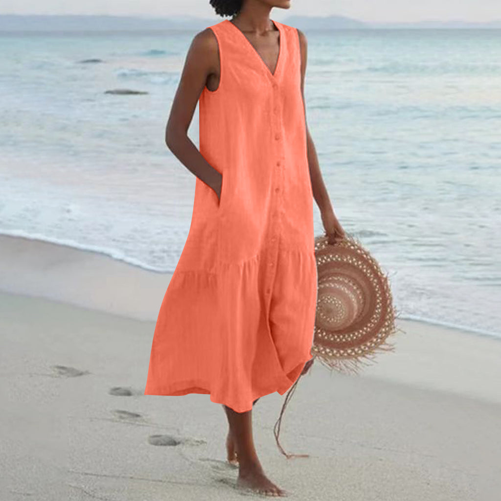 Woman in an orange dress holding a straw hat on a beach