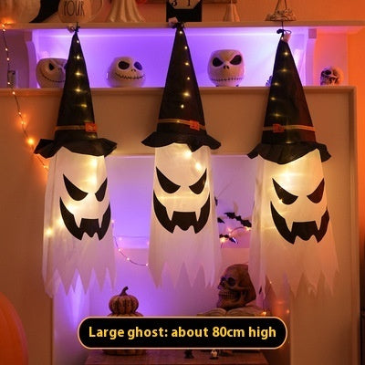 Three large ghost decorations with witch hats on a shelf with Halloween-themed decor.