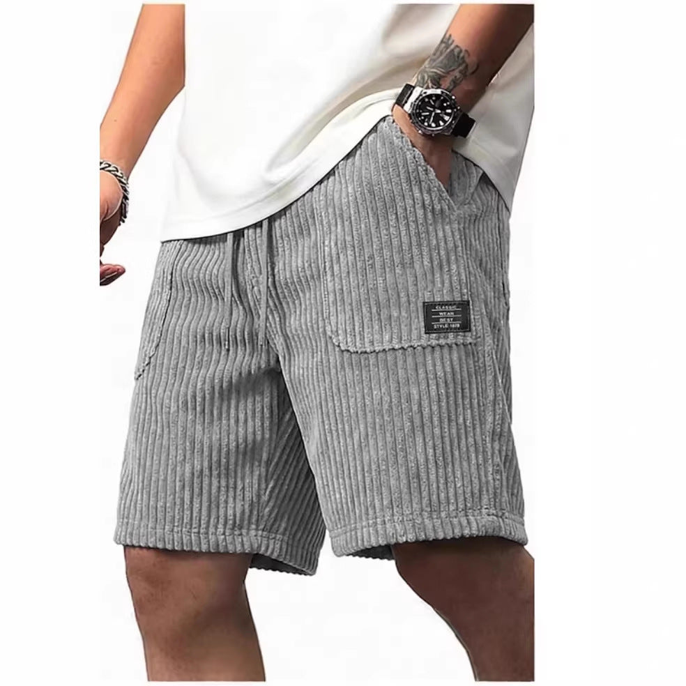Gray corduroy shorts worn by a person on a white background