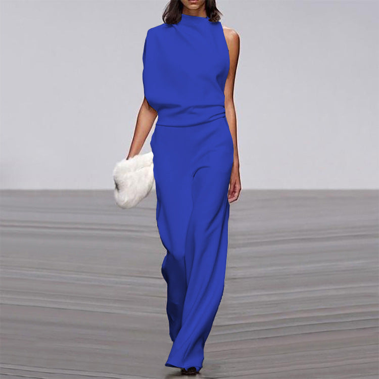 Woman wearing a blue jumpsuit on a gray floor with a white wall background