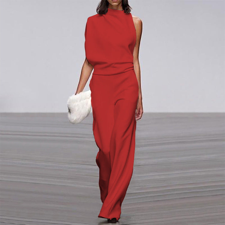 Woman wearing a red jumpsuit holding a white fur bag on a gray floor.