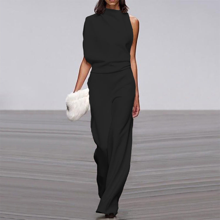 Woman wearing a black jumpsuit holding a white fur bag on a neutral background