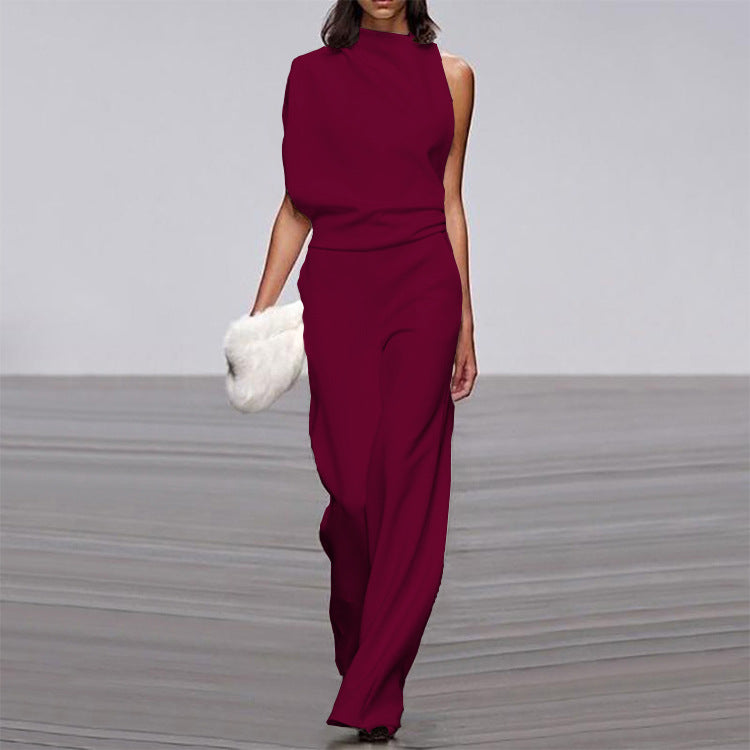 Woman wearing a burgundy jumpsuit holding a white fur bag on a gray floor.