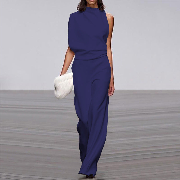 Woman wearing a blue jumpsuit on a gray floor with a white background