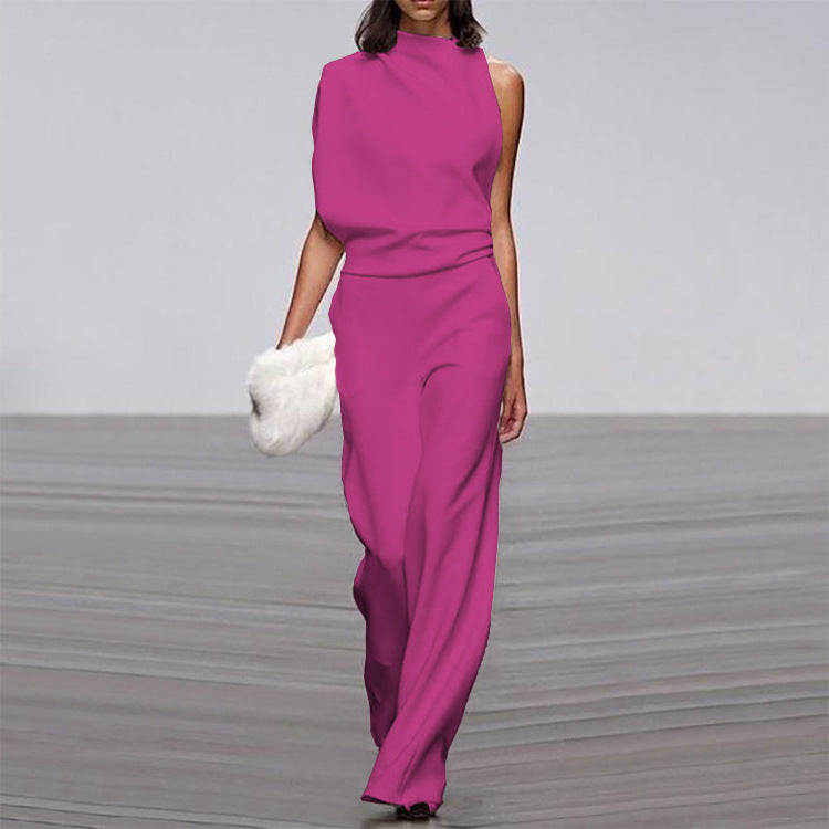 Woman wearing a vibrant pink jumpsuit holding a white fur bag on a gray floor.