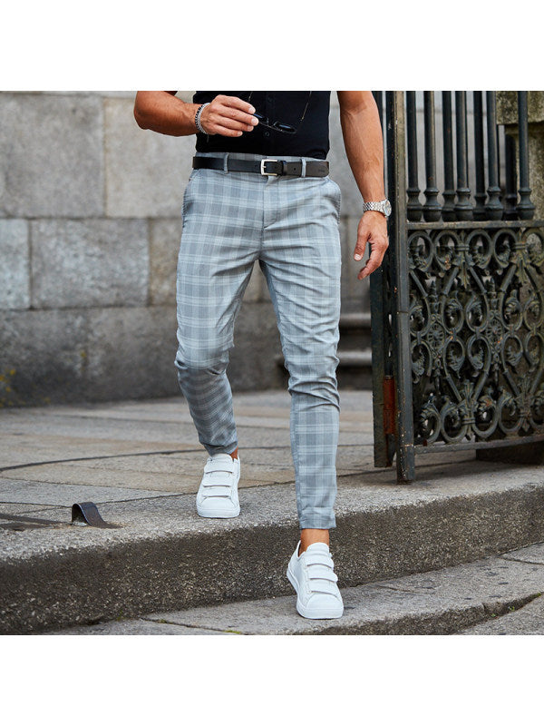 Person wearing light blue plaid pants and white sneakers on a stone staircase.
