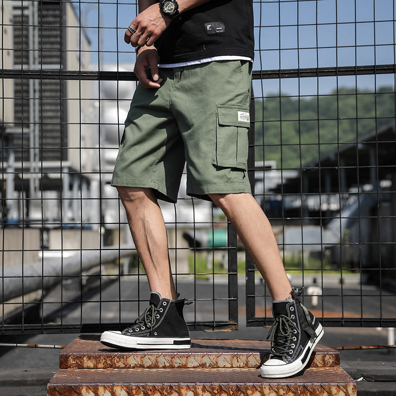 Person wearing green cargo shorts and black high-top sneakers standing on a metal platform with a blurred background.