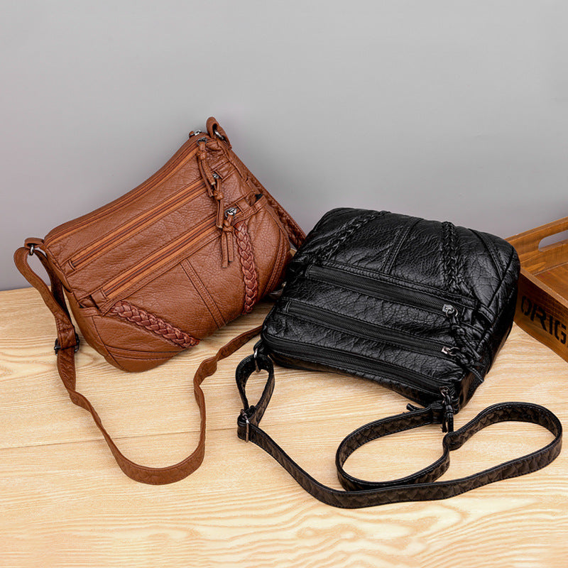 Brown and black crossbody bags on a wooden surface with a gray background