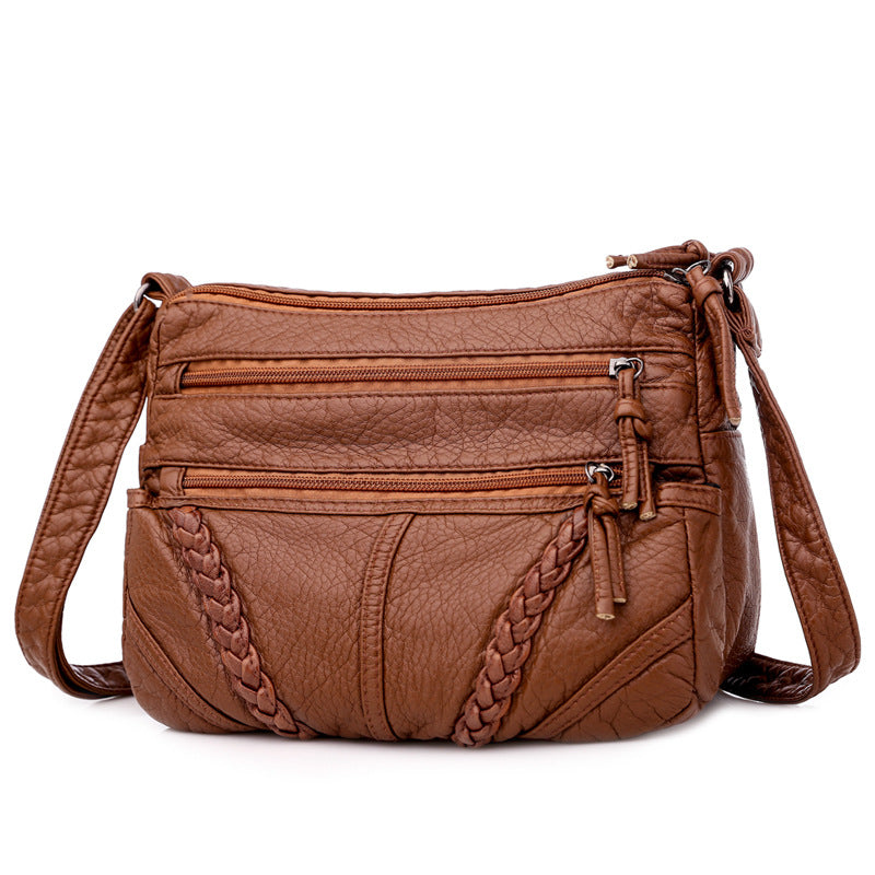 Brown leather handbag with braided details on a white background