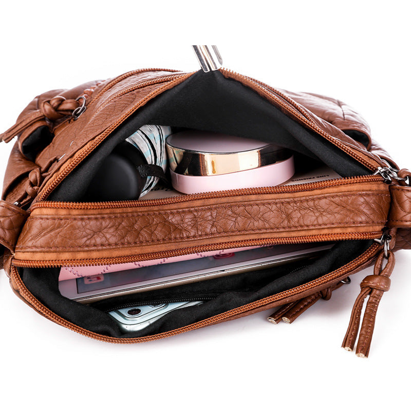 Brown leather bag with items inside on a white background