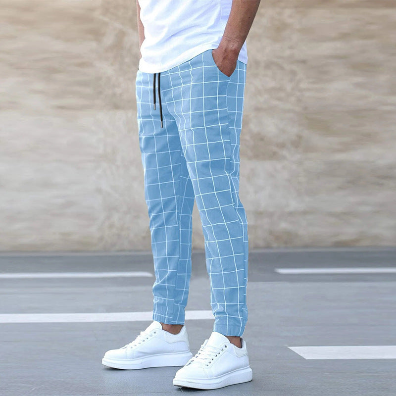 Person wearing light blue checkered pants and white sneakers on a neutral background