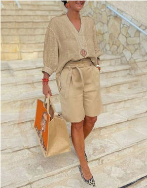 Woman in beige outfit holding a patterned bag on a stone staircase