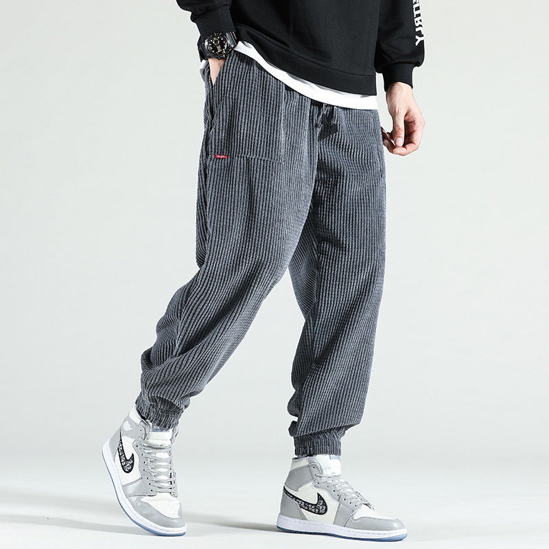 Person wearing gray checkered pants and white sneakers on a light gray background