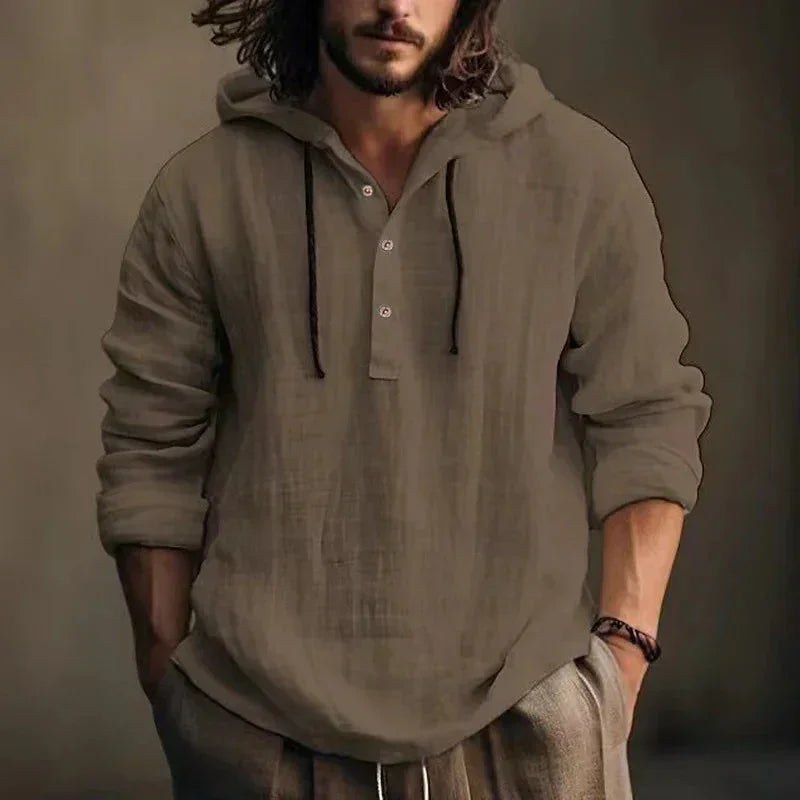 Man wearing a brown hooded shirt against a neutral background