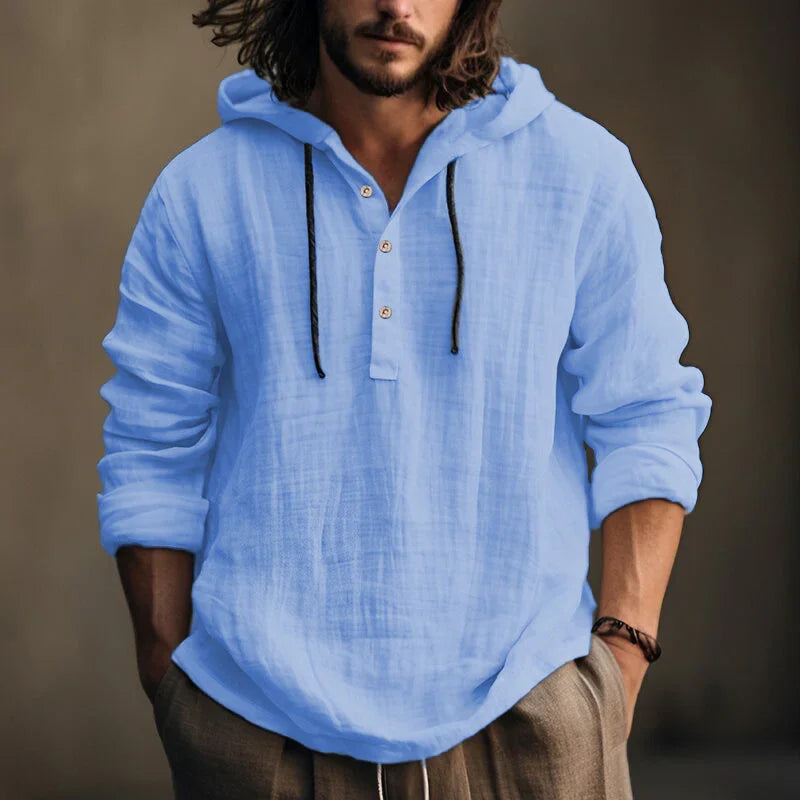 Man wearing a light blue hooded shirt against a brown background
