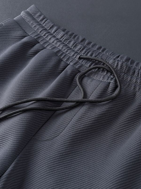Dark grey textured drawstring sweatpants with elastic waistband, close-up view