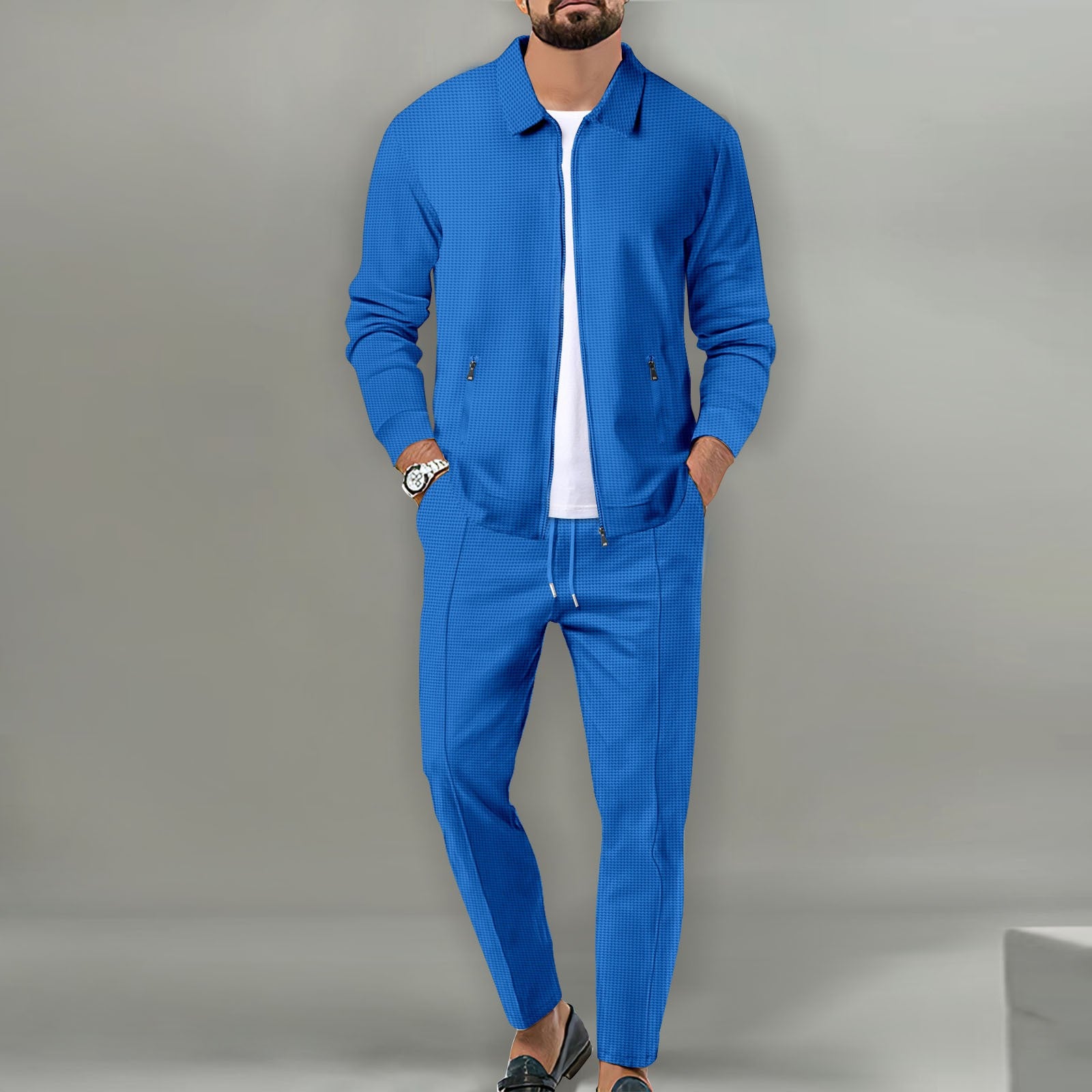 Man wearing a blue tracksuit against a gray background