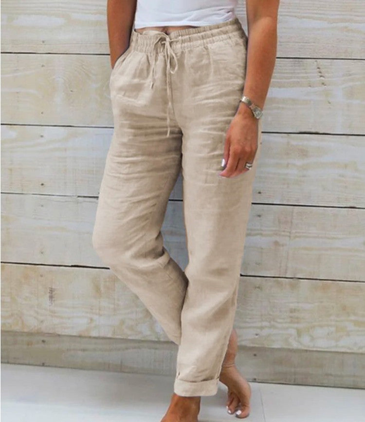 Beige linen pants worn by a person against a wooden background