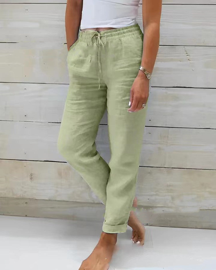 Person wearing light green pants and a white top against a wooden background