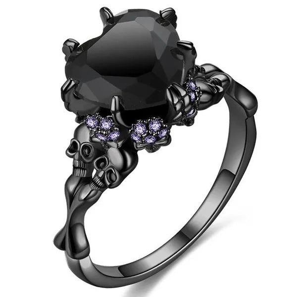 Black skull ring with a large black gemstone and smaller purple stones on a white background