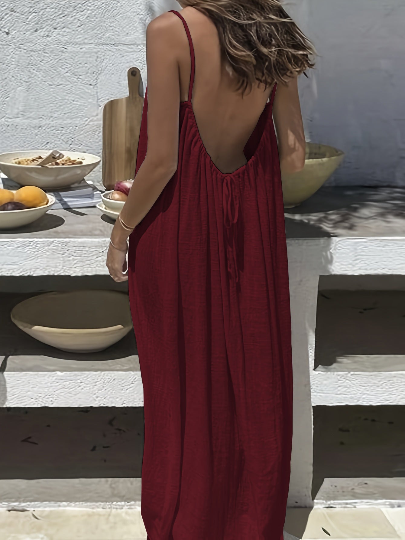 Woman in a red dress standing outdoors near a table with food.